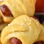 Pinterest graphic of pigs in a blanket. Text says "super easy pigs in a blanket simplejoy.com" Image shows pigs in a blanket topped with salt.