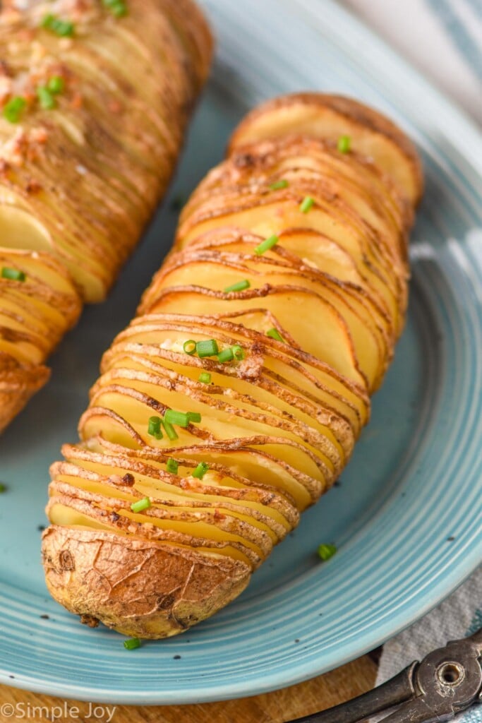 Overhead of hasselback potatoes on a plate garnished and ready for serving.