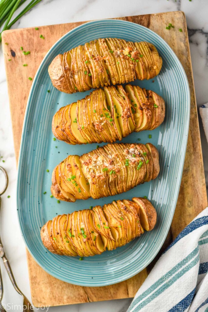 Overhead of hasselback potatoes on a plate garnished and ready for serving.