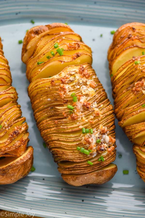 Overhead of hasselback potatoes on a plate garnished and ready for serving.
