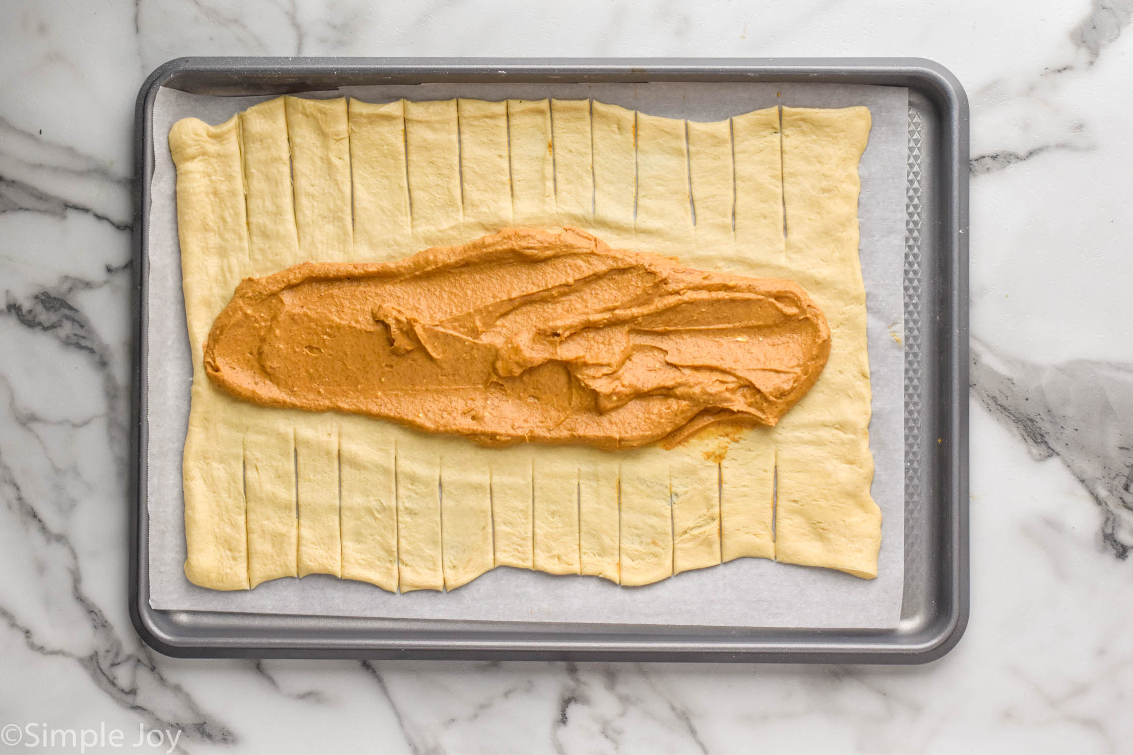 Overhead photo of Pumpkin Cheesecake Braid laying open on a baking sheet ready for braiding and baking.