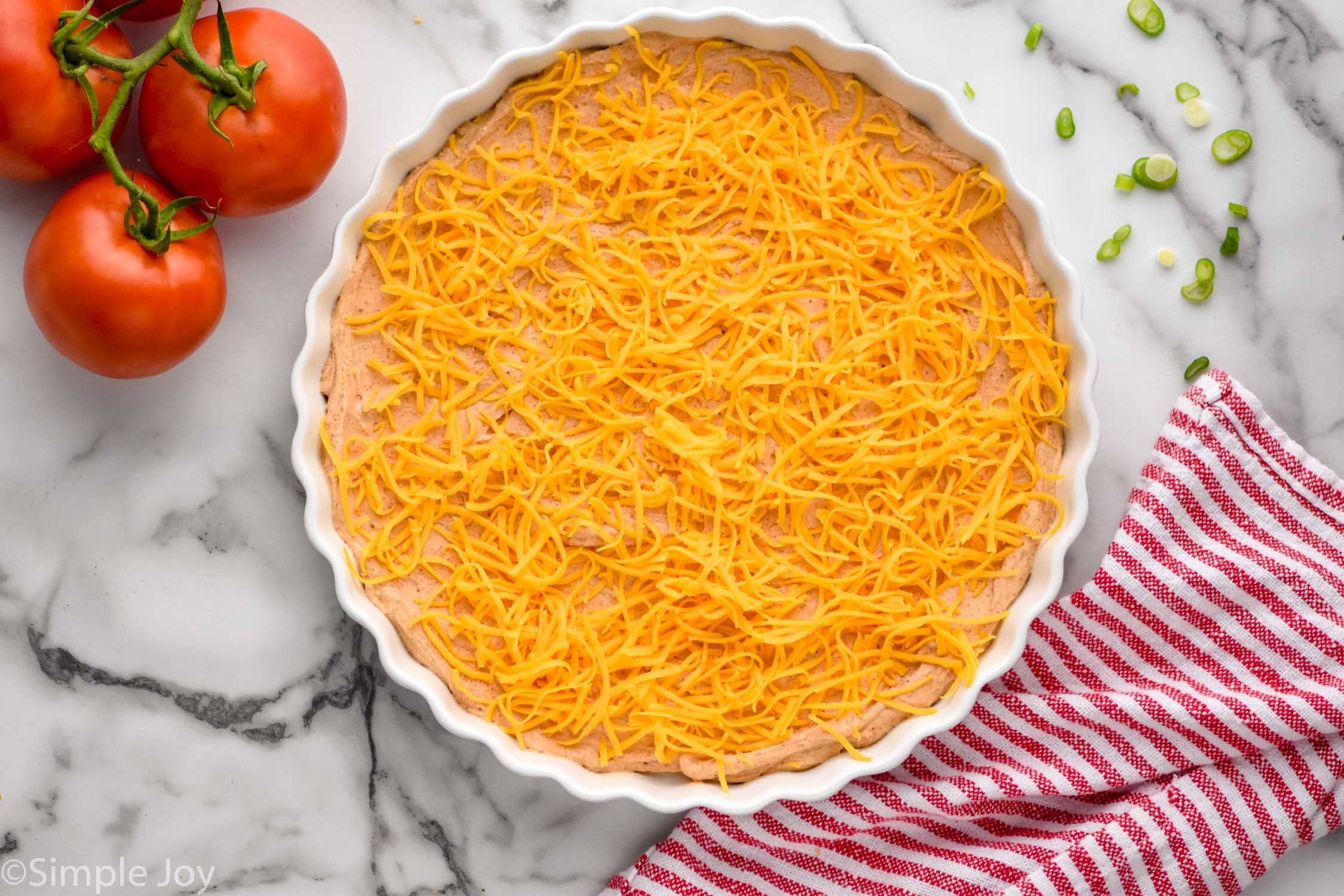 Overhead photo of Taco Dip recipe in process with the cheese layer on top