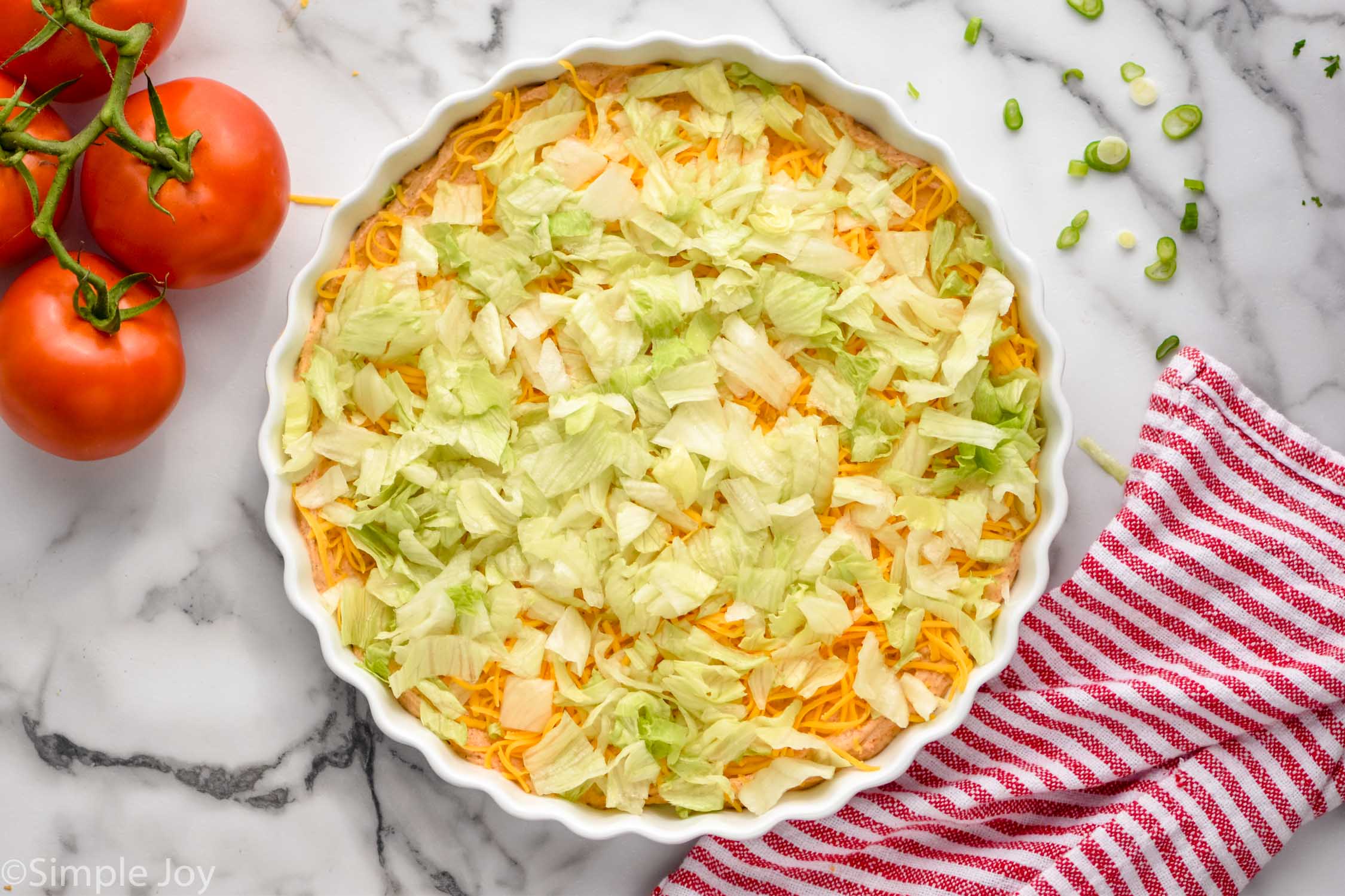 Overhead photo of Taco Dip recipe in process with the lettuce layer on top.