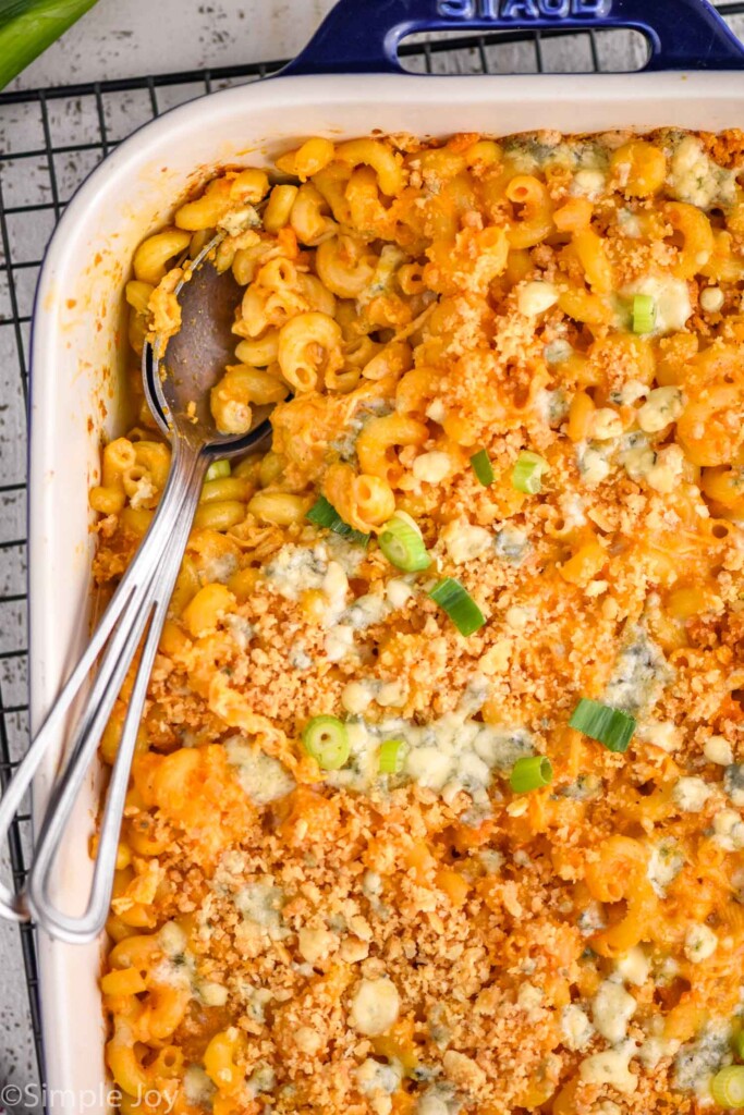 Overhead photo of a baking dish of Buffalo Chicken Mac and Cheese with a spoon for serving.