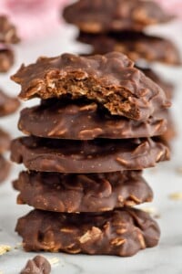 Photo of a stack of No Bake Chocolate Oatmeal Cookies with a bite out of the top cookie.