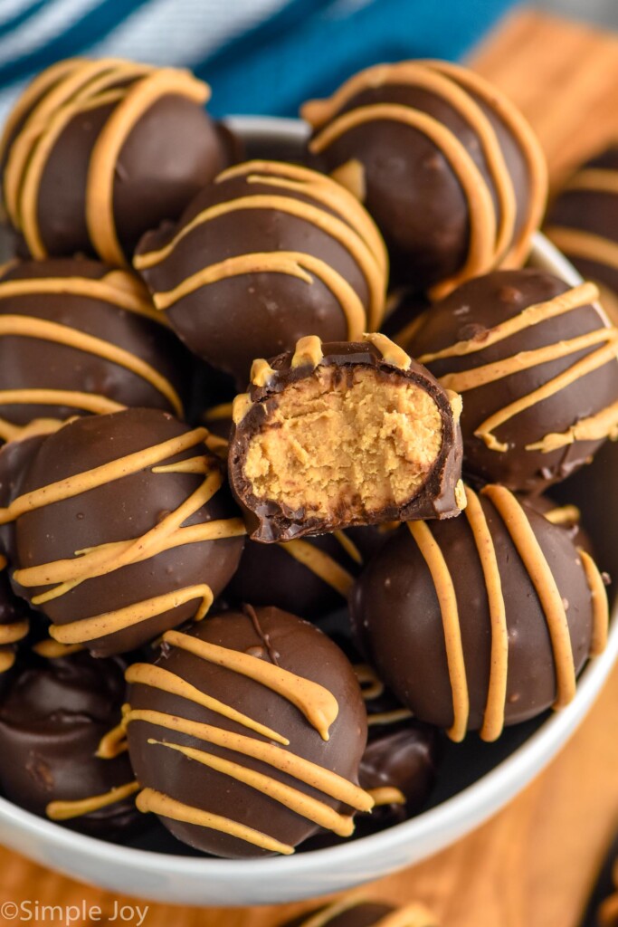Overhead photo of Peanut Butter Balls in a bowl. One Peanut Butter Ball has a bite taken out.