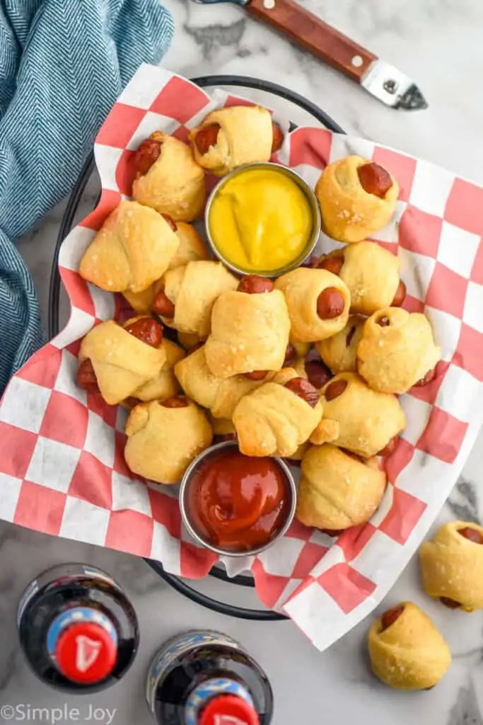 overhead of pigs in a blanket appetizer recipe with cups of ketchup and mustard