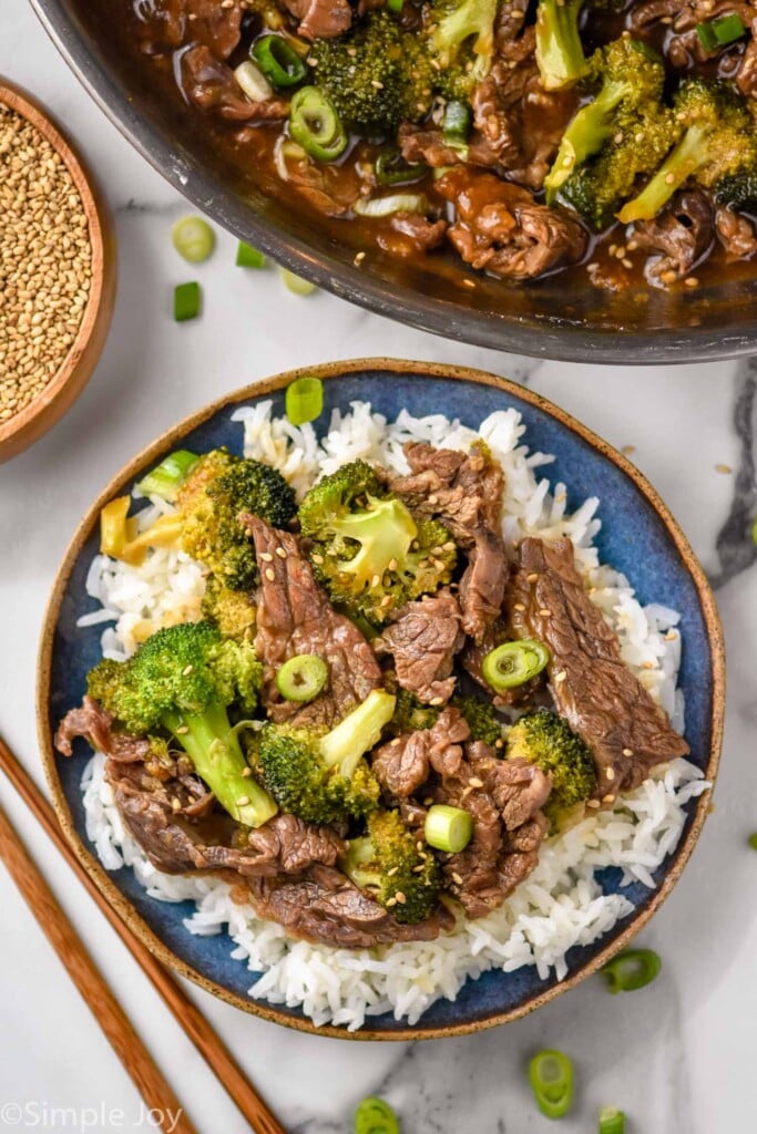 overhead of a bowl of beef teriyaki with broccoli served over rice. Pan of beer teriyaki recipe sitting beside.