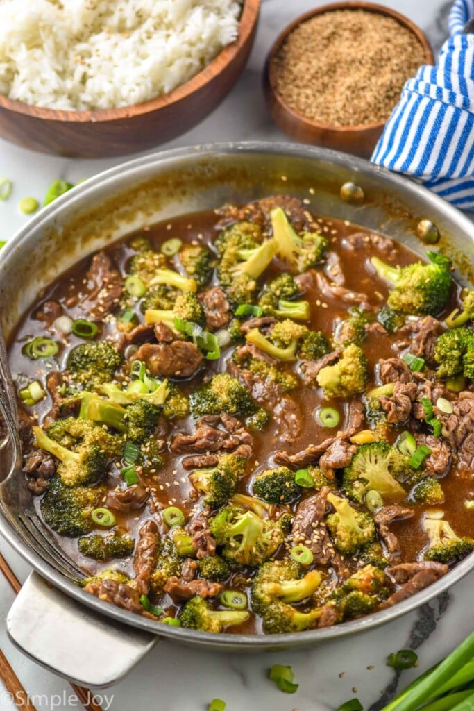 overhead of pan of beef teriyaki with broccoli. Bowl of rice sitting in background for serving.