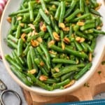 pinterest graphic of a serving platter of green beans almondine, says: "super easy green beans almondine"