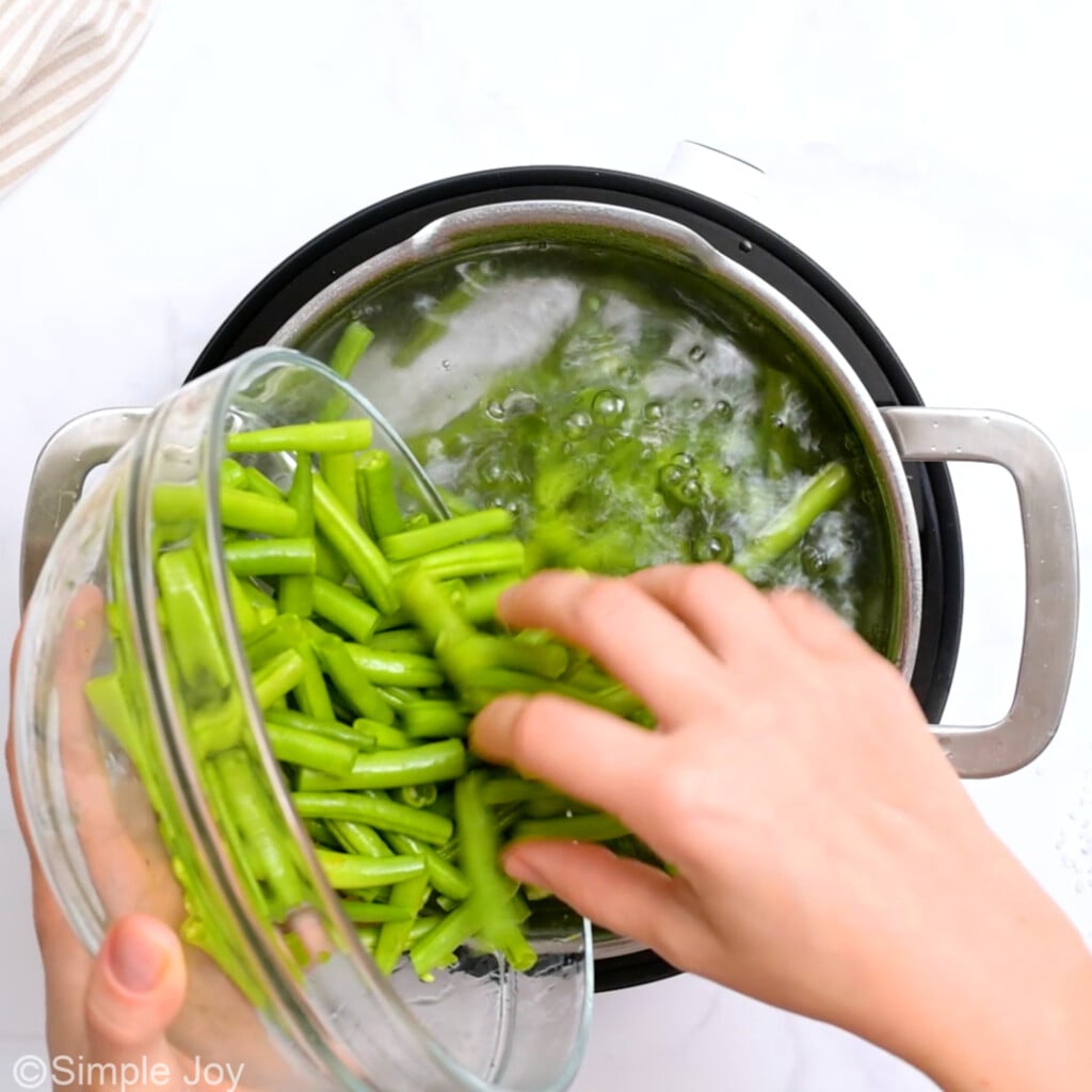 green beans being poured into a pot of boiling water