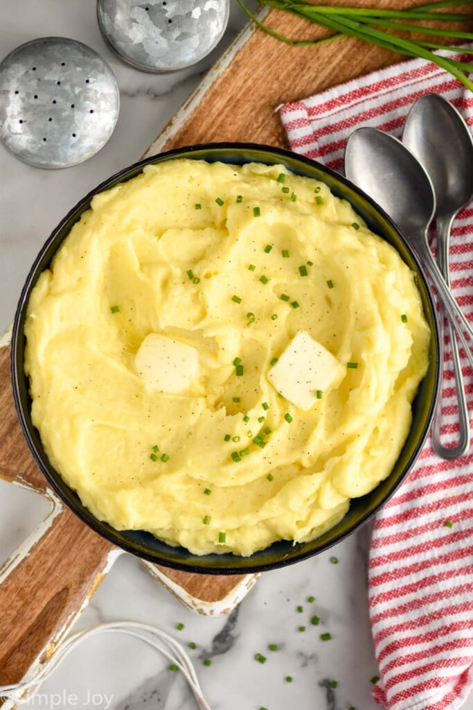 overhead bowl of mashed potatoes with two spoons and salt and pepper shaker sitting beside