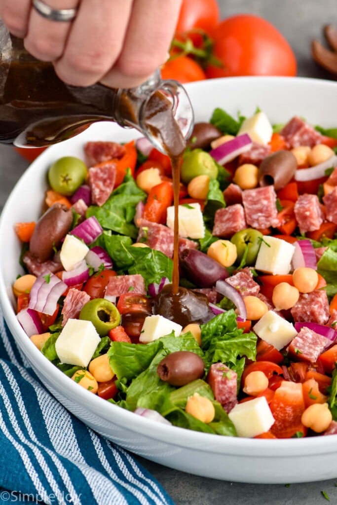 balsamic dressing being poured over a chopped salad recipe