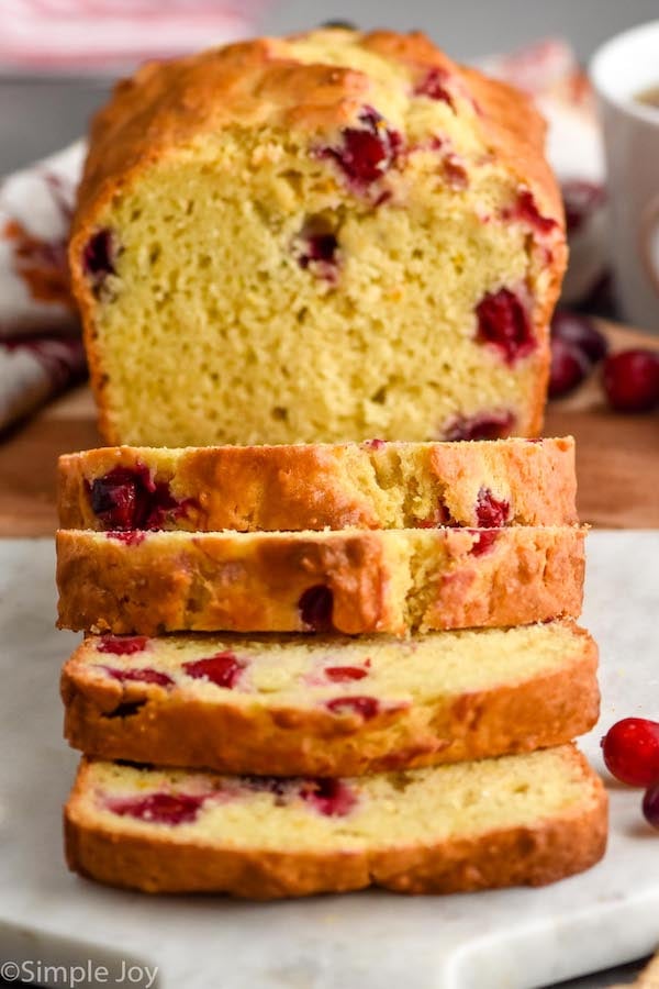 sliced loaf of orange cranberry bread sitting on cutting board for serving.