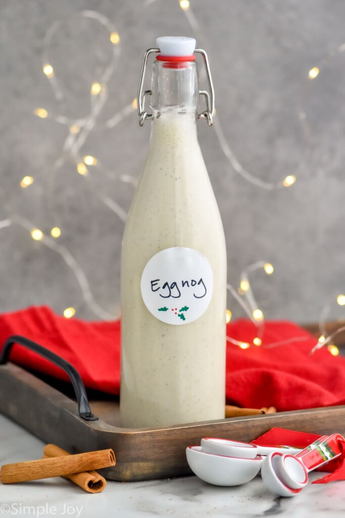 Bottle of homemade eggnog with a red towel and sparkling lights in the background
