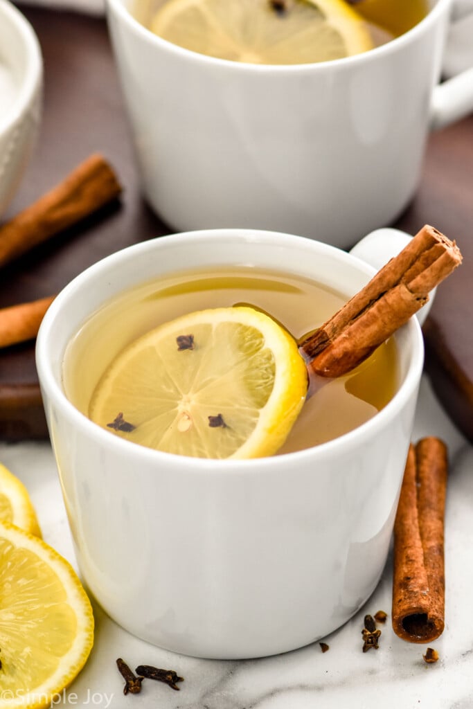 Overhead photo of a Hot Toddy in a white mug with a cinnamon stick and lemon slice in the mug and around the mug