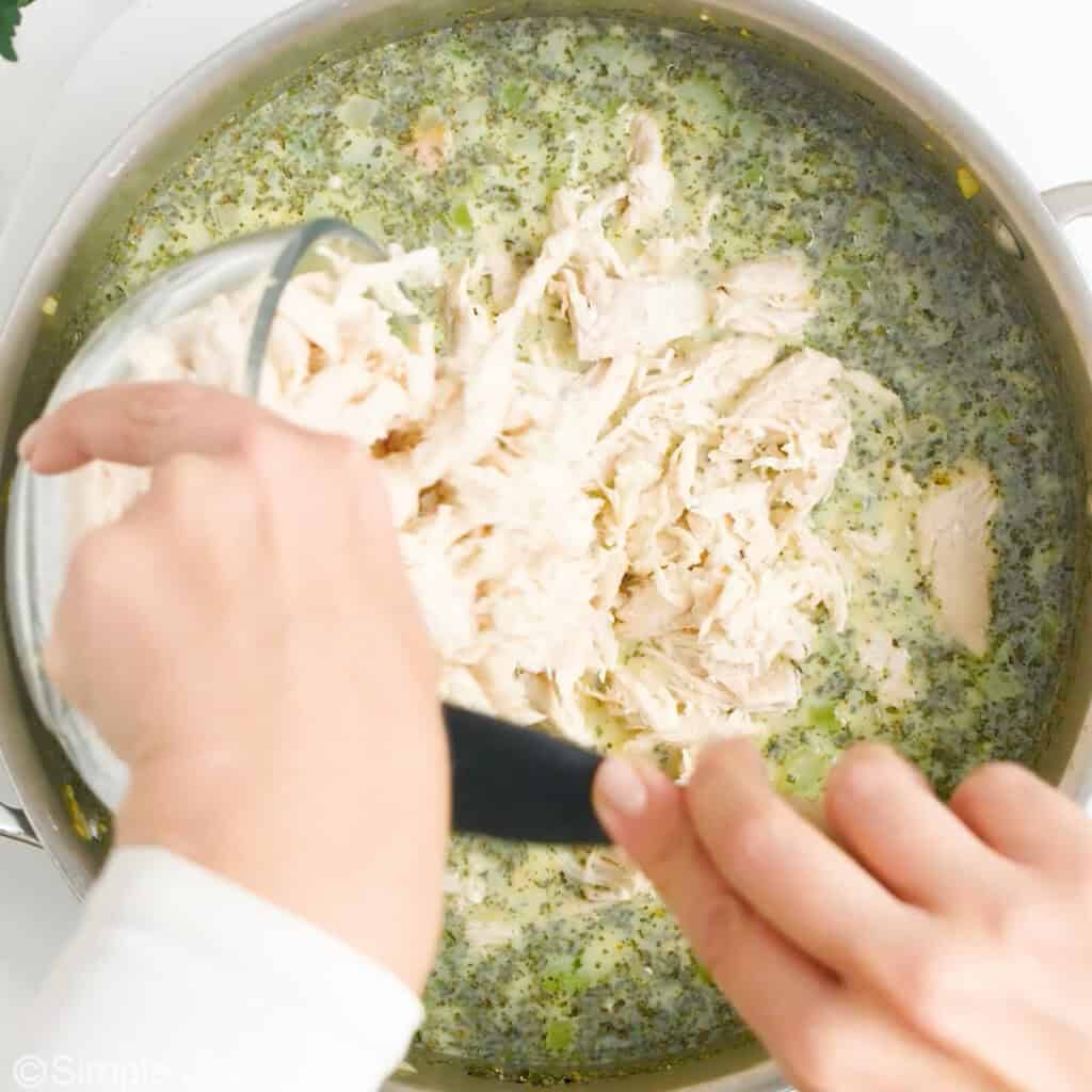 pouring shredded chicken into a sauce
