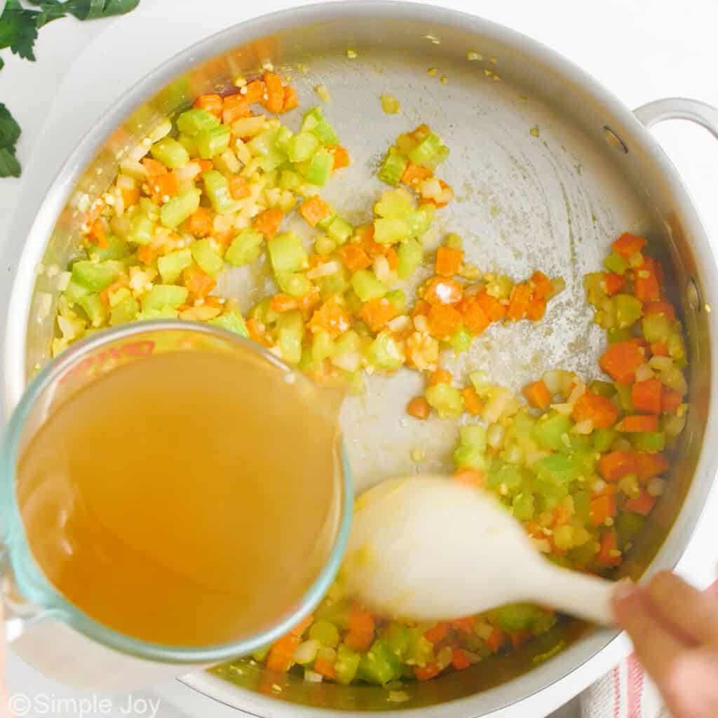 adding chicken broth to a skillet of sautéed vegetables
