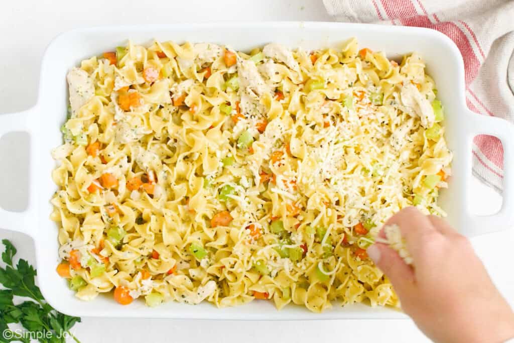 spreading cheese over the top of an unbaked chicken noodle casserole