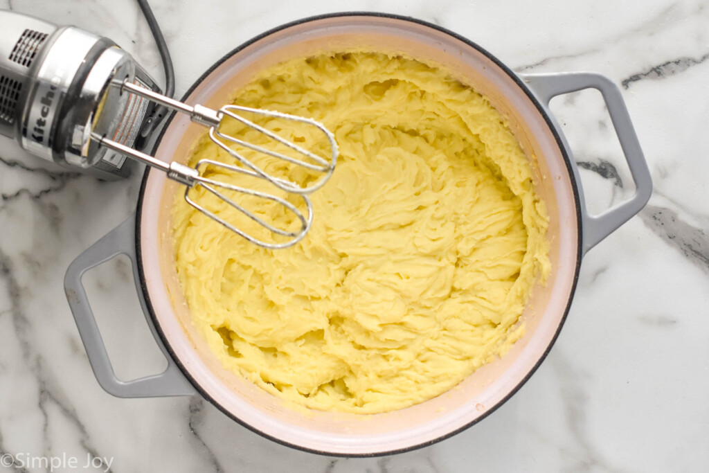 overhead pot of mashed potatoes with hand mixer sitting beside