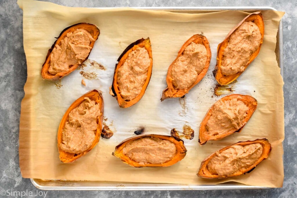 Overhead photo of filled sweet potatoes on a baking sheet for Twice Baked Sweet Potatoes recipe.