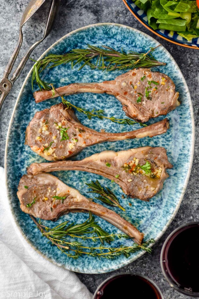 overhead photo of easy lamb chops and a white and blue pan with herbs around it.