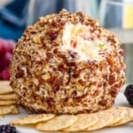 pineapple cheese ball on a serving board surrounded by crackers and fresh berries - 9