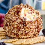 pineapple cheese ball on a serving board surrounded by crackers and fresh berries