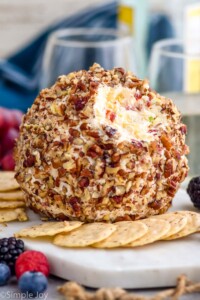 pineapple cheese ball on a serving board surrounded by crackers and fresh berries