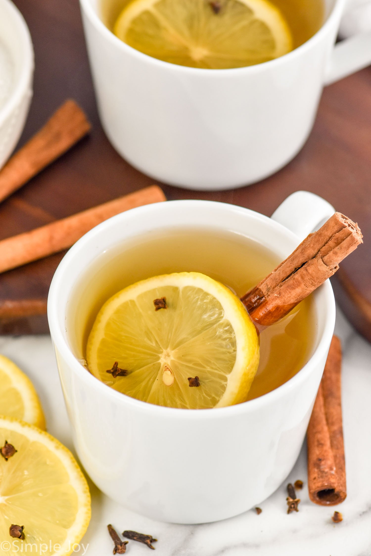 Overhead photo of a Hot Toddy in a white mug with a cinnamon stick and lemon slice in the mug and around the mug