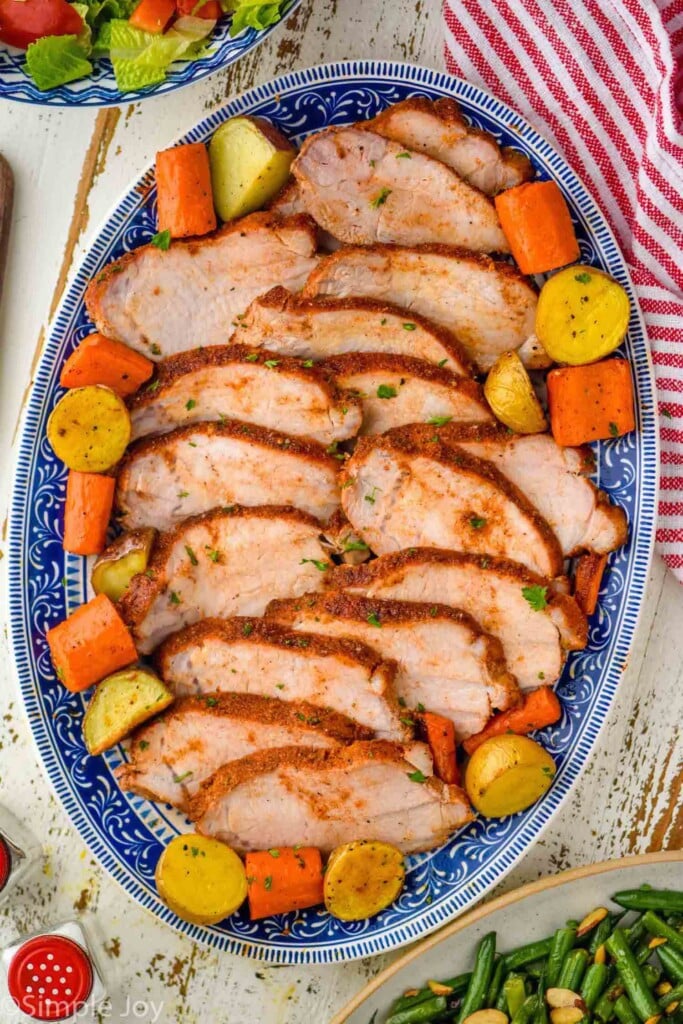 overhead of sliced pork roast , carrots, and potatoes on a platter for serving