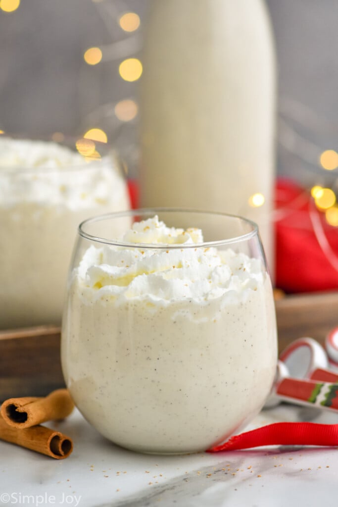 Spiked eggnog photo in a stemless wine glass with sparkling lights in background