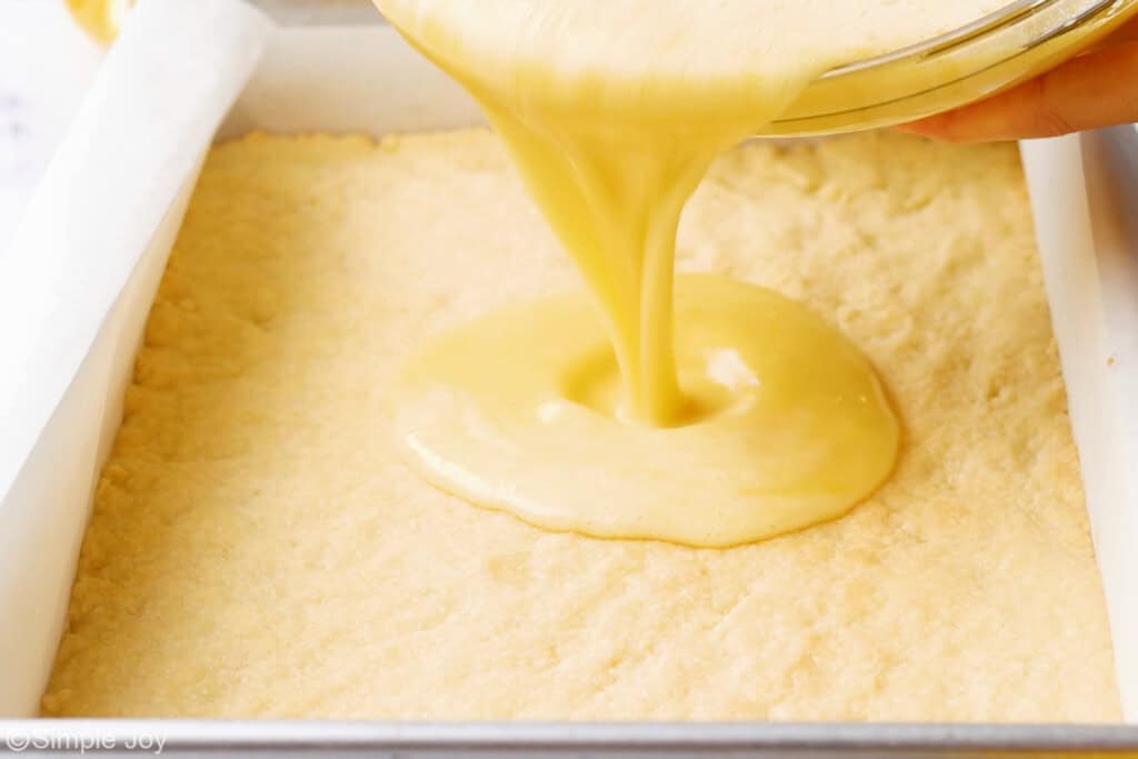 lemon filling being poured over a shortbread crust