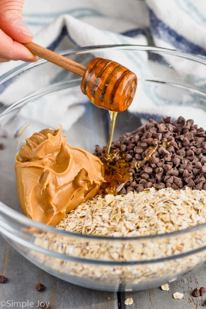 honey being poured into ingredients for oatmeal energy bites