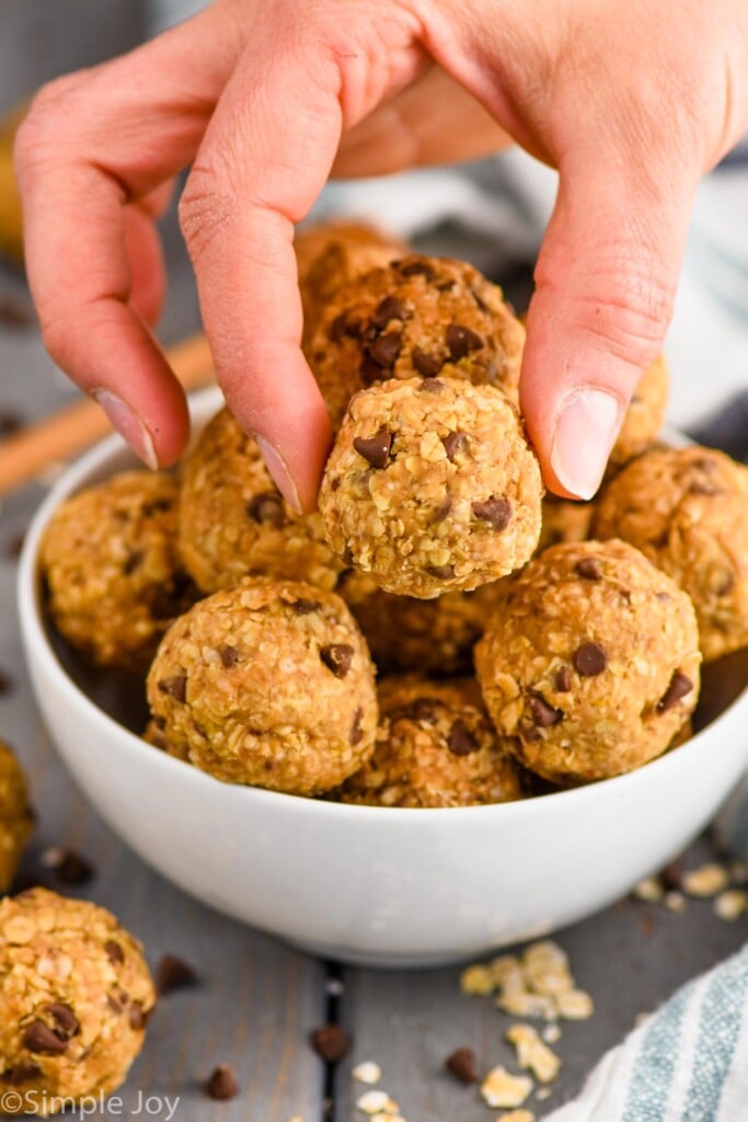 fingers setting down peanut butter energy balls into a bowl