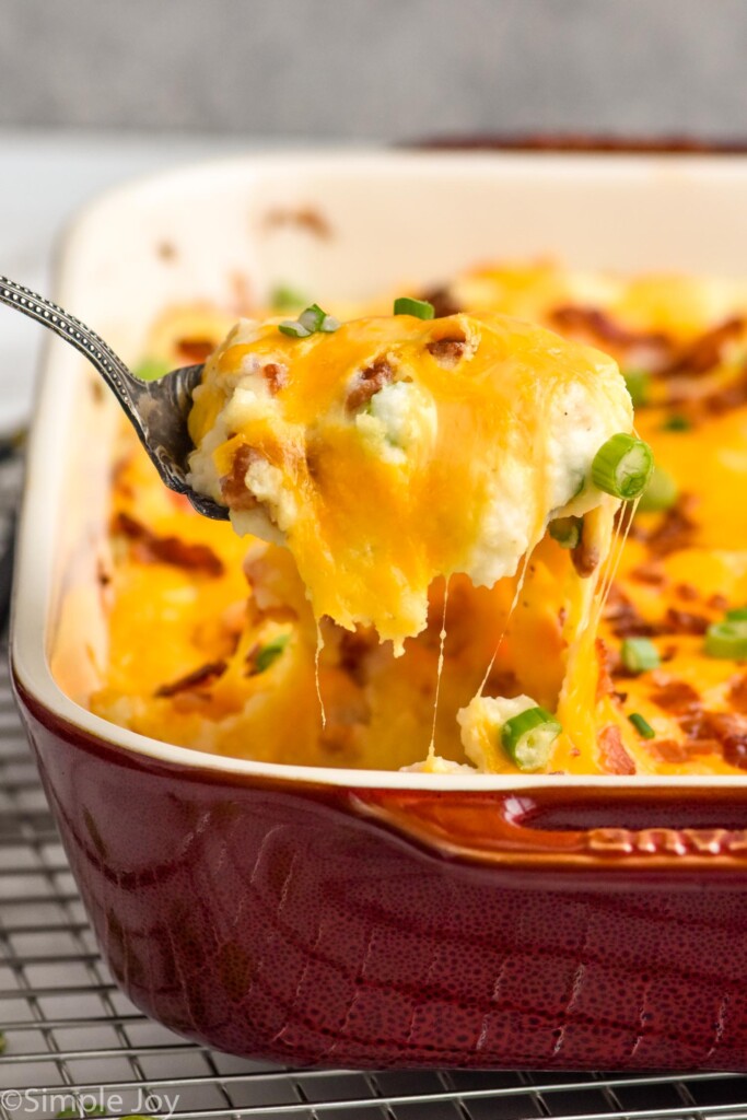 Overhead photo of a spoon scooping Twice Baked Potato Casserole out of baking dish.
