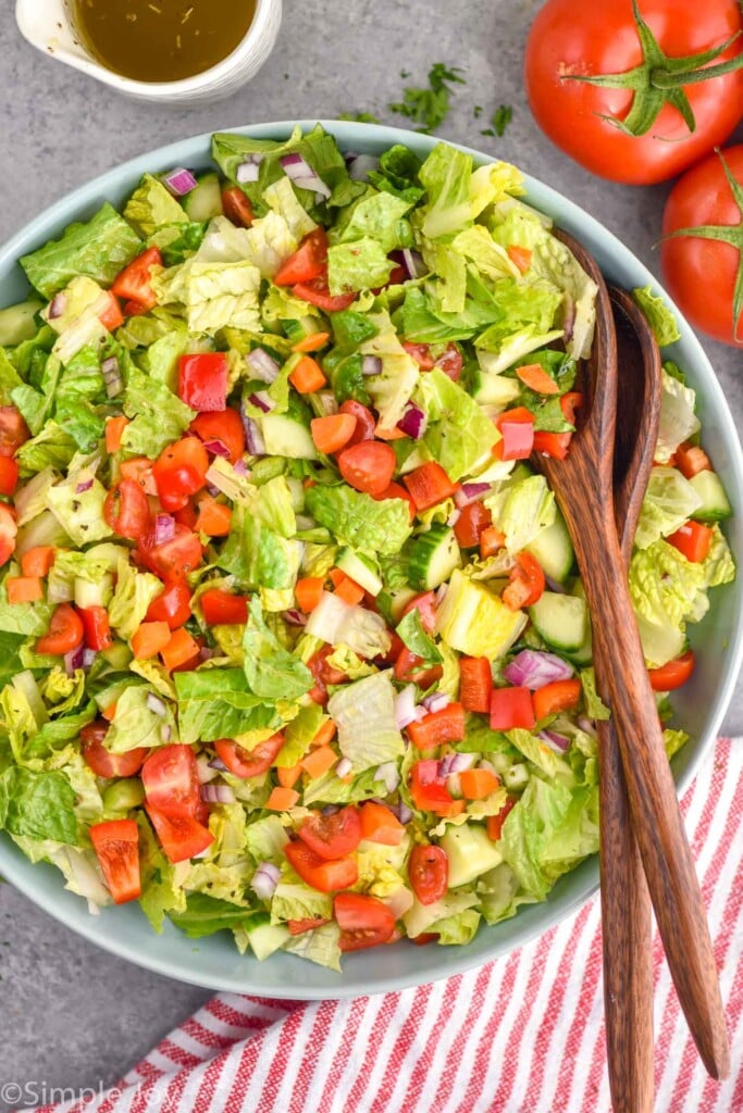 Overhead photo of Chopped Salad with salad tongs and dressing for serving.