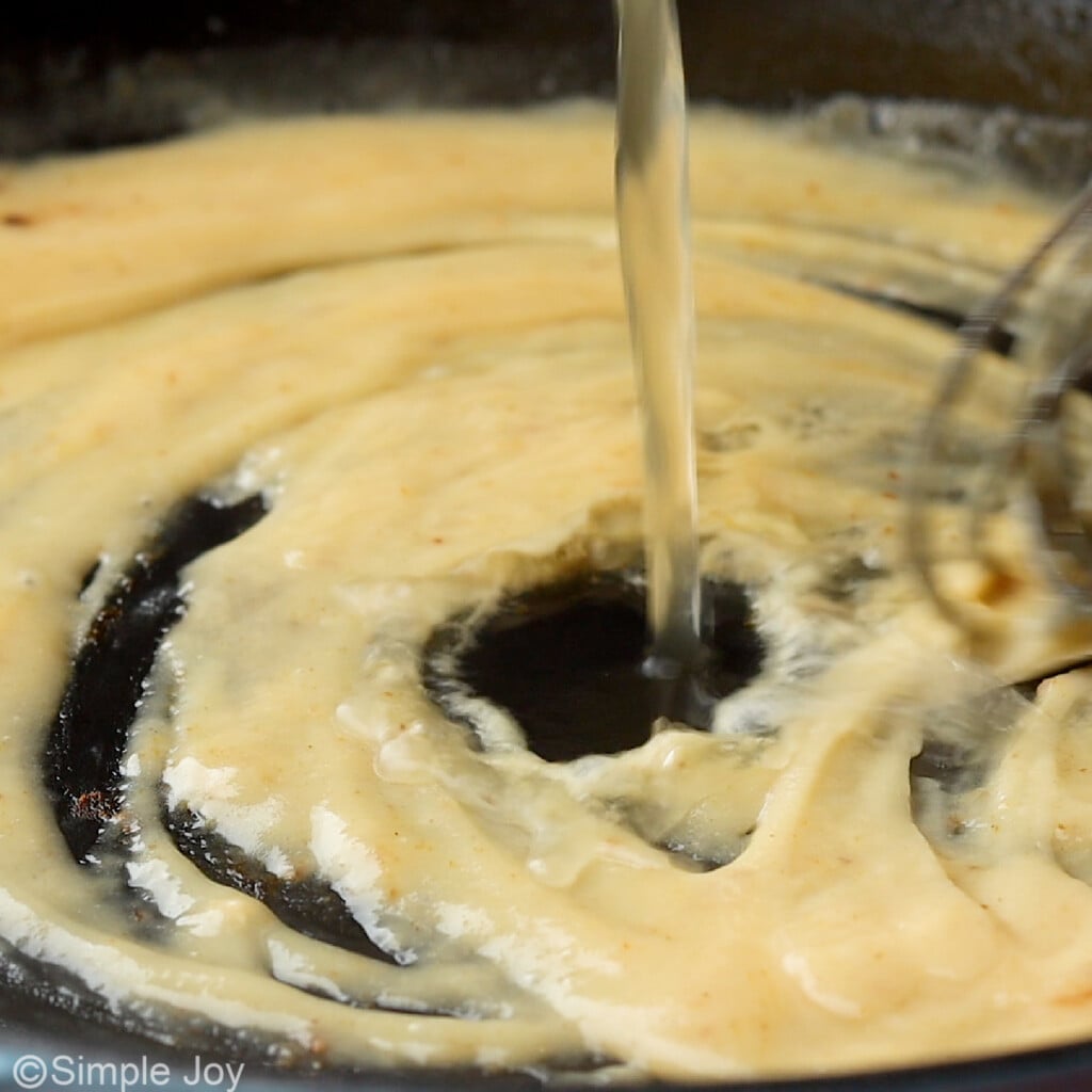 close up photo of white wine being poured into a skillet