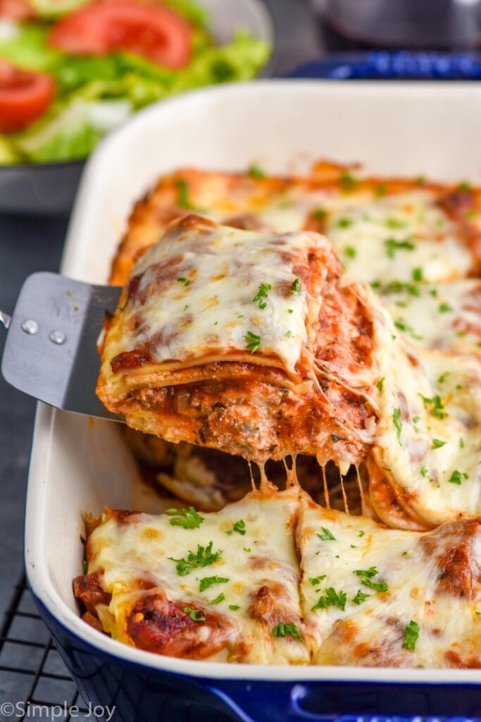 Close up photo of a spatula scooping out a piece of Homemade Lasagna from a baking dish.
