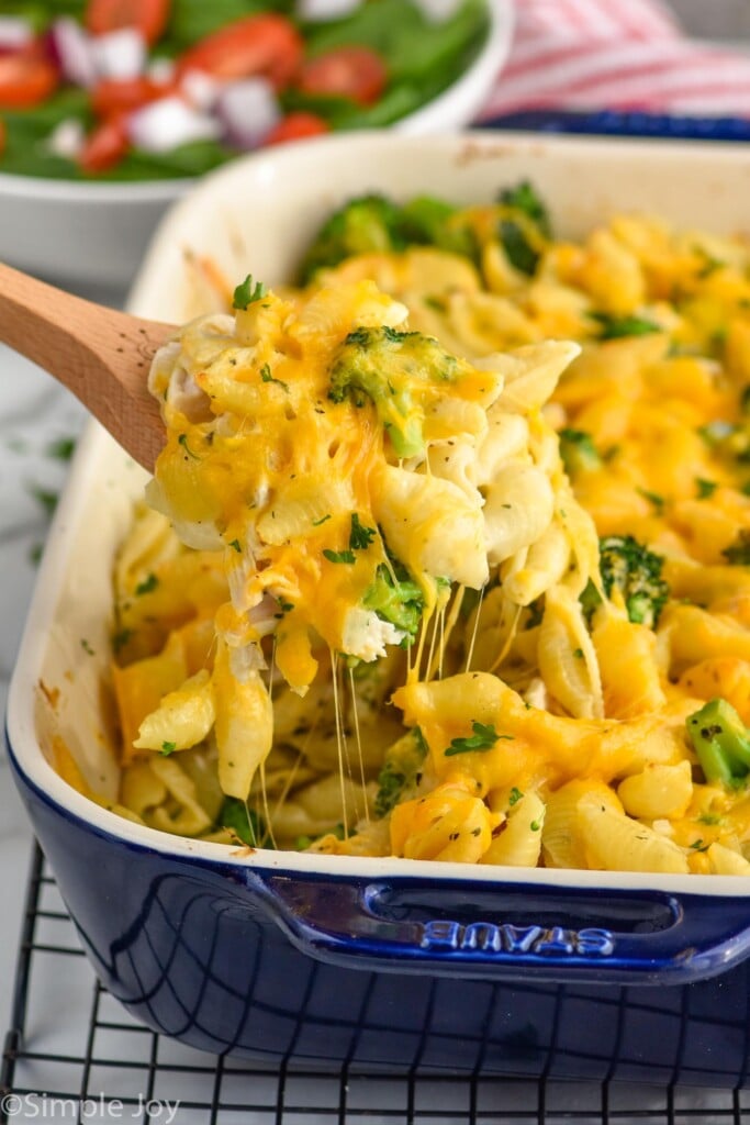 Close up photo of a spoon scooping out Chicken Broccoli Noodle Casserole from baking dish.