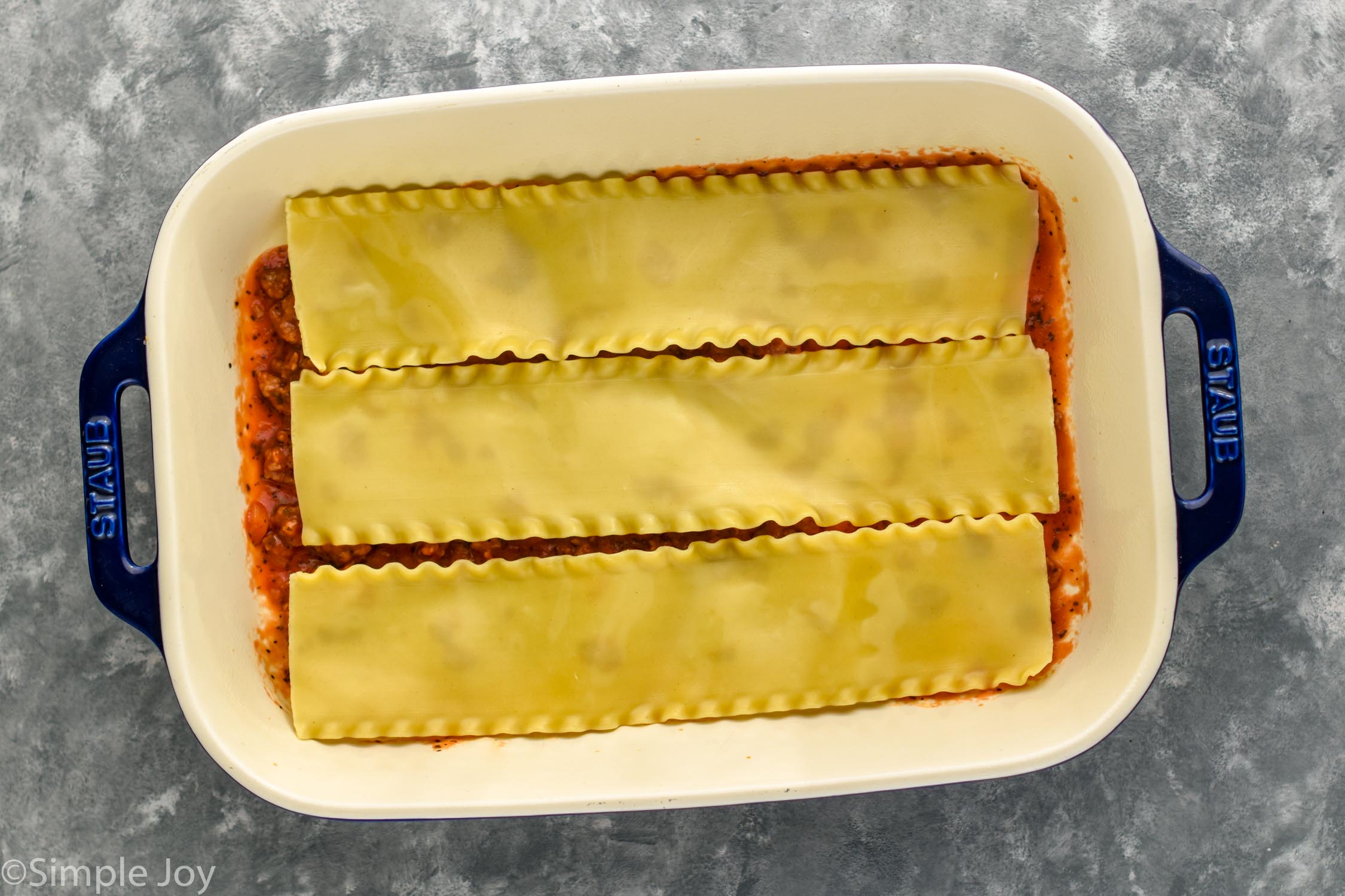 Overhead photo of baking dish of ingredients for Homemade Lasagna recipe.