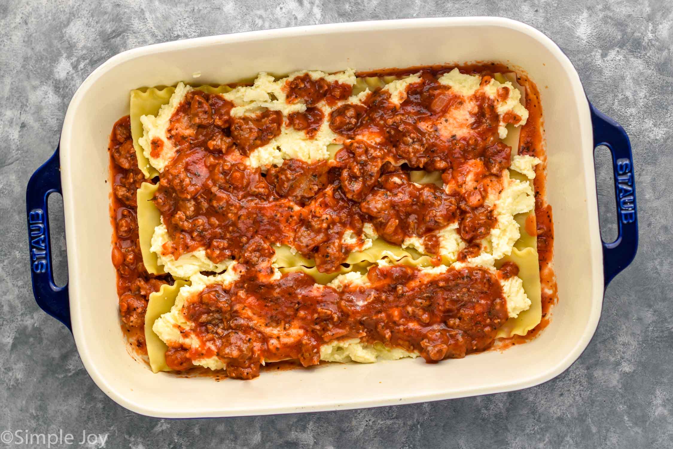 Overhead photo of a baking dish of ingredients for Homemade Lasagna recipe.