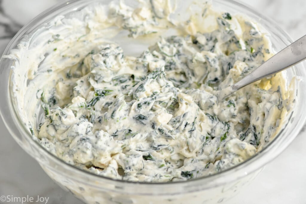 bowl of spinach dip being mixed together