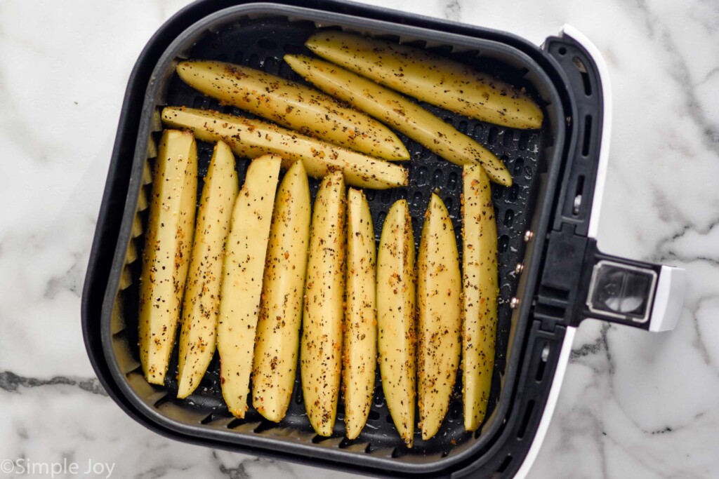 Overhead photo of Air Fryer Potato Wedges in air fryer basket ready for cooking.