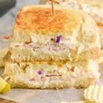 Close up photo of a Rachel Sandwich sliced in half and served with potato chips. - 8