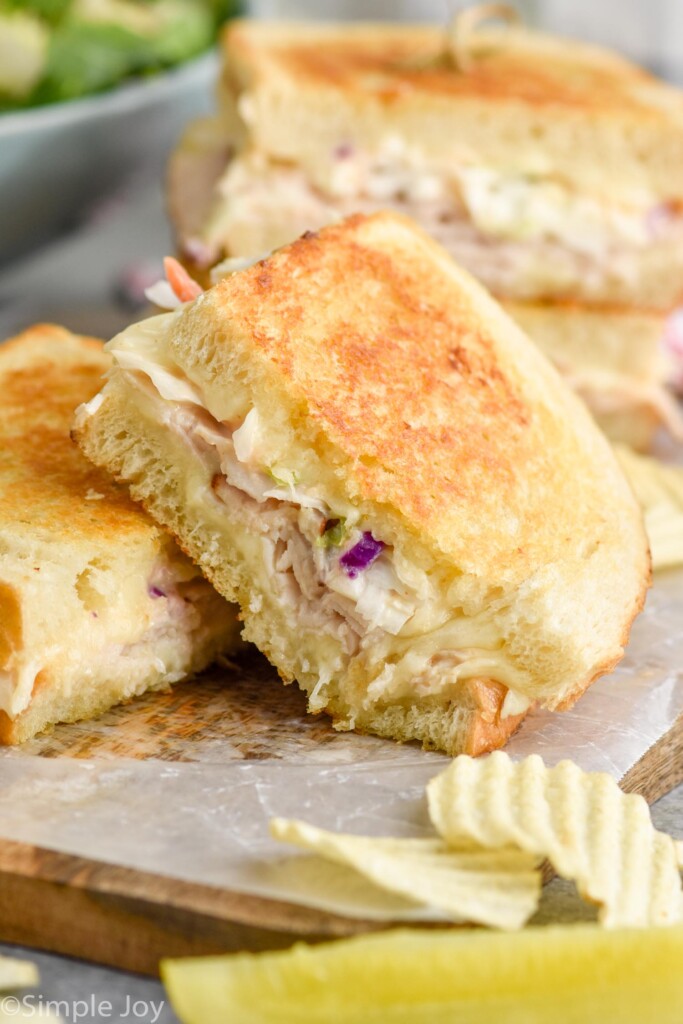 Close up photo of Rachel Sandwich cut in half and served with a pickle spear and potato chips.