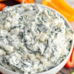 Overhead photo of Spinach Dip Recipe served in a bowl. Sliced peppers, cucumbers, and chips beside bowl for dipping. - 9