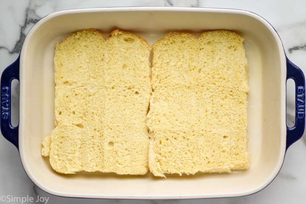 Overhead photo of a baking dish with dinner rolls for Pizza Sliders recipe.