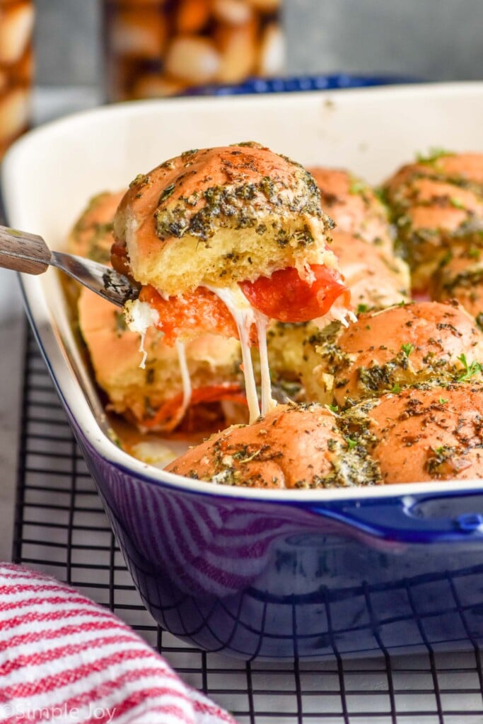 Photo of Pizza Sliders being scooped out of baking dish of Pizza Sliders.