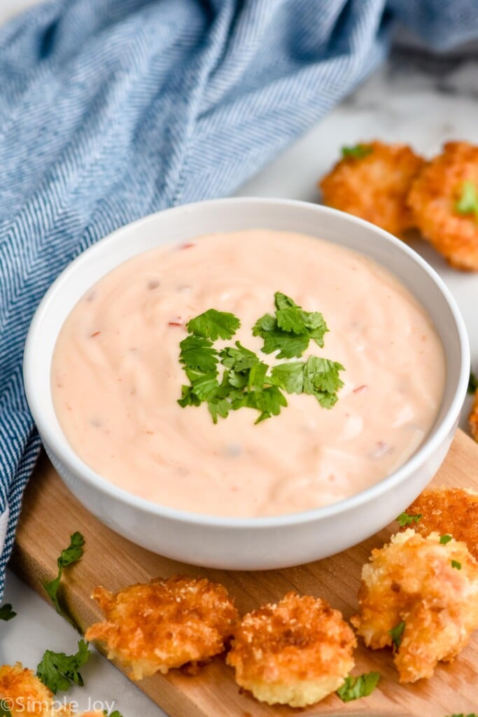 Overhead photo of a bowl of Bang Bang Sauce garnished with cilantro. Shrimp lay beside bowl for dipping.